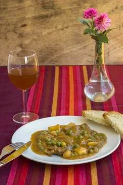 Table with typical Catalan stew of beef with potatoes and peas, accompanied b Stock Photos