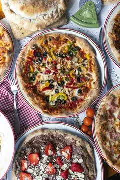 Table with various types of pizza. Vertical image Stock Photos