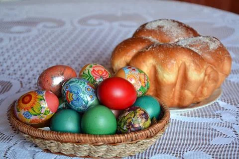 A table with a weave basket with multicolored dyed eggs and a sweet bread Stock Photos