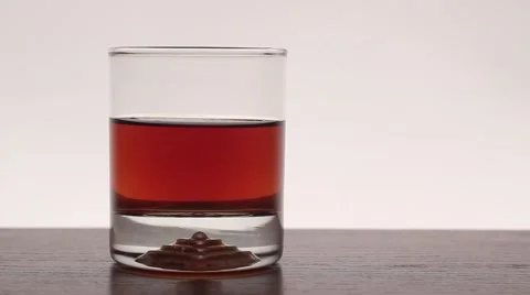 On the table is a whiskey with ice. The ice falls into the glass. Video stock 59311084