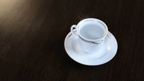 On the table is a white cup with boiling water. Brewed black tea bag. Stock Footage 128429097