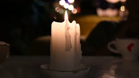 On the table a white large candle burns slowly close-up video 4k Stock Footage 136039874