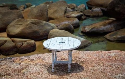 Table white round on the background of large stones in the sea Stock Photos