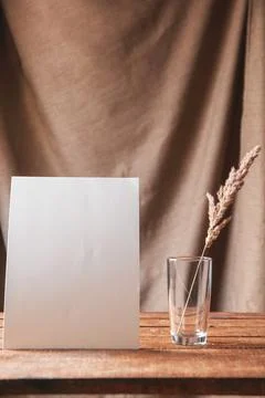 On the table is a white sheet of paper with dried flowers in a glass. Stock Photos