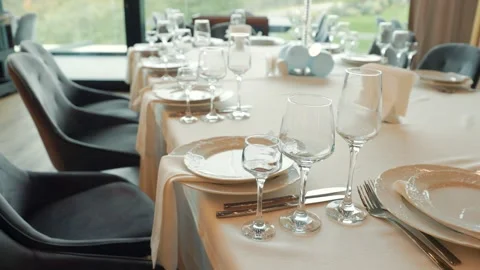 Table with a white tablecloth and a number of plates, forks, knives Stock Footage 299360480
