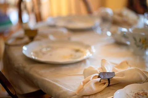 A table with a white tablecloth and a white napkin with a black ring on it Foto stock