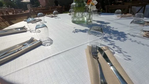 Table with white tablecloth served with cutlery, glasses, napkins and flowers. Stock Footage 199034277