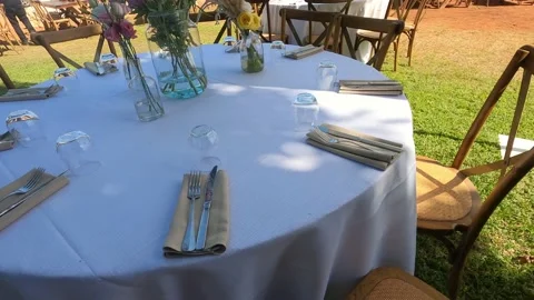 Table with white tablecloth served with cutlery, glasses and napkins and flowers Stockbeeldmateriaal 199034282