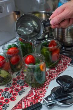 On a tablecloth with a traditional pattern sits a jar into which boiling wa.. Stock Photos