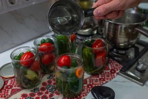 On a tablecloth with a traditional pattern sits a jar into which boiling wa.. Stock Photos