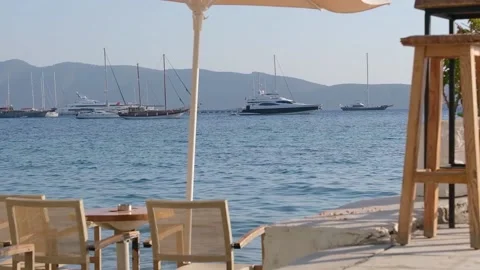 Tables and chairs are on the beach. In the background of the yacht Stock Footage 228708194