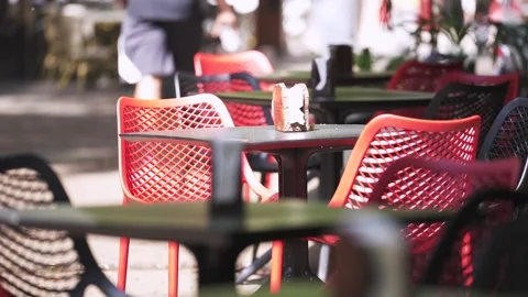 Tables and chairs of an empty cafe in the summer morning. People pass by Stock Footage 240646960