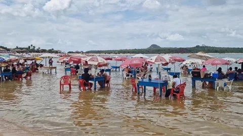 Tables of bars standing in the water at the beach in Alter do Chao in Brazil Stock Footage 303444291