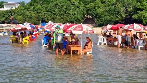 Tables of bars standing in the water at the beach in Alter do Chao in Brazil Stock Footage 303444370