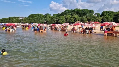 Tables of bars standing in the water at the beach in Alter do Chao, Brazil Stock Footage 304994396