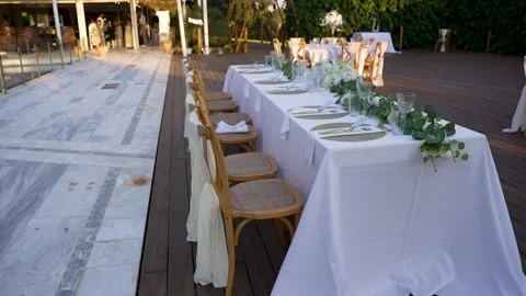 Tables set for a gathering on a wooden deck with greenery in the background Stock Footage 345283786