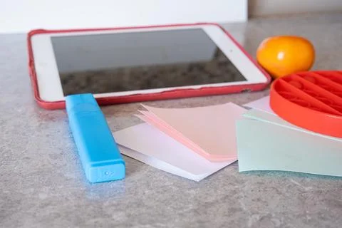 Tablet alongside highlighter, layered paper sheets, sensory fidget toy Stock Photos