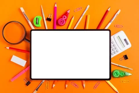 Tablet and Assorted School Supplies on Orange Background Stock Photos