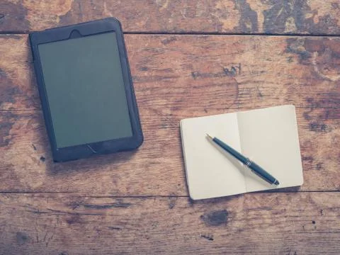 Tablet and pen with notepad on table Photos
