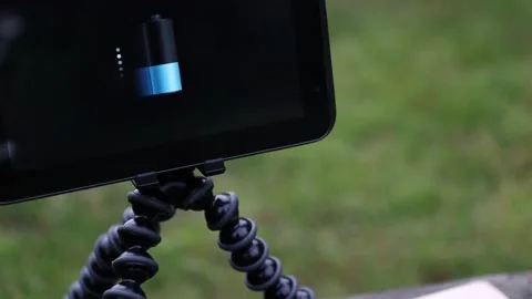 Tablet and smartwatch is charging from wireless power bank on the bench. Stock Footage 157875929