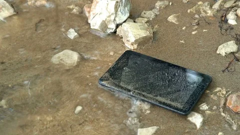 A tablet on the banks of the river is washed by the wave Stock Footage 76536440