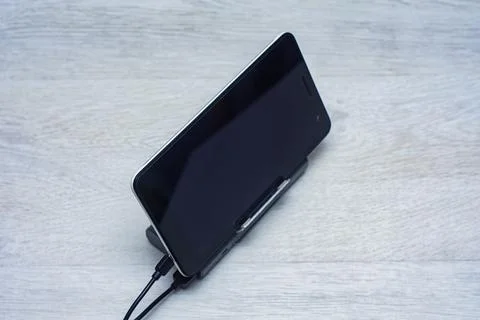 The Tablet is being charged using a portable charger on a wooden table. Stock Photos