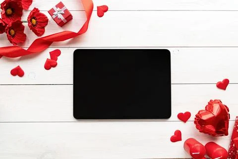 Tablet with black screen with valentine decorations candles, balloons and con Stock Photos