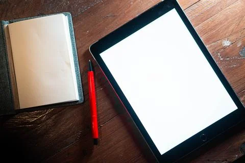 Tablet with blank screen and notebook on wooden table Stock Photos