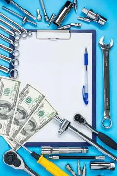 Tablet with a blank sheet, dollars and wrenches around. Auto repair invoice c Stock Photos
