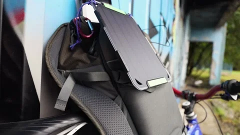 Tablet is charged from a portable solar panel battery attached to backpack. Stock Footage 157333210