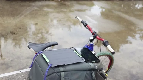 Tablet is charged from a portable solar panel battery attached to backpack. Stock Footage 157333248