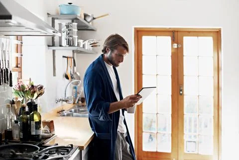 Tablet, coffee and man in kitchen for online connection, social networking and Stock Photos