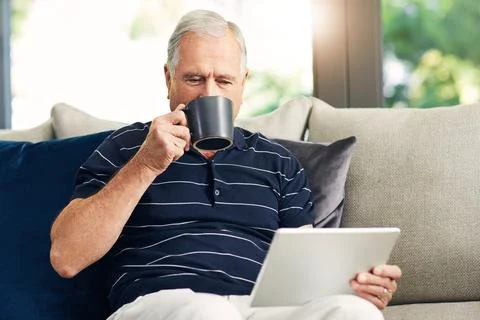Tablet, coffee and old man in home to relax, reading news article and digit.. Stock Photos