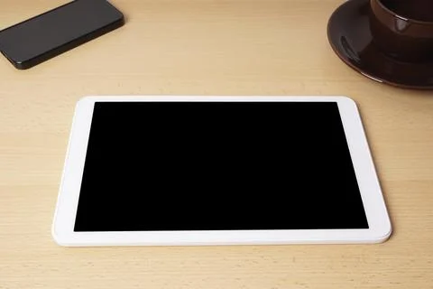 Tablet computer with blank screen lying on desk with smartphone and coffee cup Stock Photos
