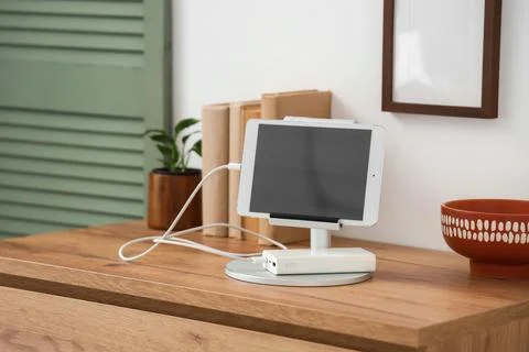 Tablet computer charging from power bank on shelf in room Stock Photos