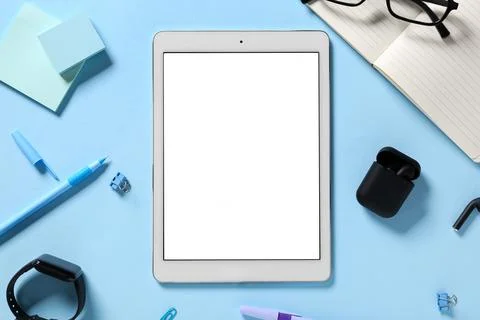 Tablet computer with different modern gadgets and stationery on blue backgrou Stock Photos