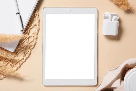 Tablet computer with earphones, notebook and pampas grass on beige background Stock Photos