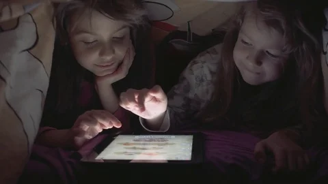 Tablet computer in the hands of little girls. Children play hiding under the Stock Footage 74090111