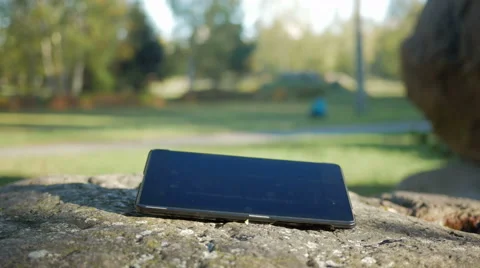 Tablet computer is on a large stone in the street. Man's hand in a green jacket Stock Footage 68572342