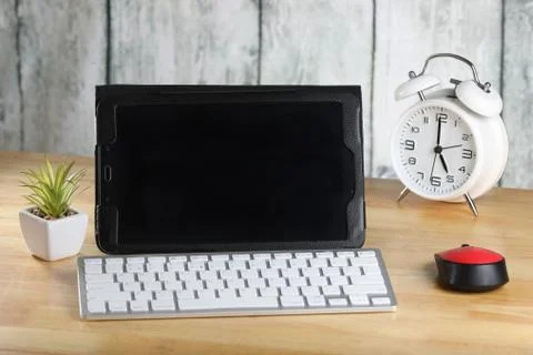 Tablet, computer mouse and keyboard on a table. Retro alarm clock. Stock Photos