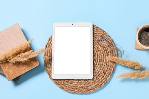 Tablet computer with notebook, pampas grass and cup of coffee on blue backgro Stock Photos