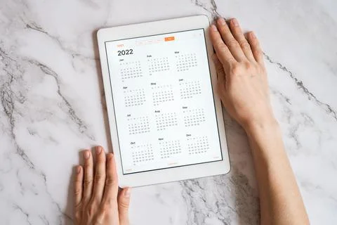 Tablet computer with an open app of calendar for 2022 year in a womans hands  Foto stock