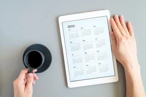 Tablet computer with open app of calendar for 2022 year in a womans hands and Stock Photos
