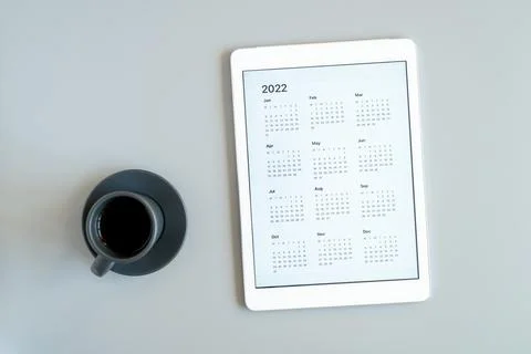 Tablet computer with an open app of calendar for 2022 year and cup of tea or  Stock Photos