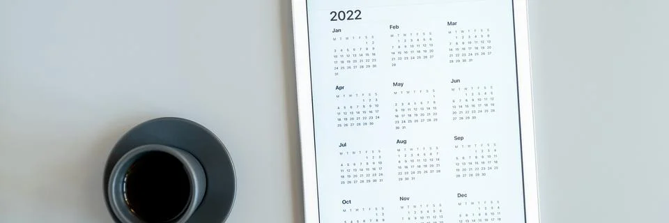 Tablet computer with an open app of calendar for 2022 year and cup of tea or  Stock Photos