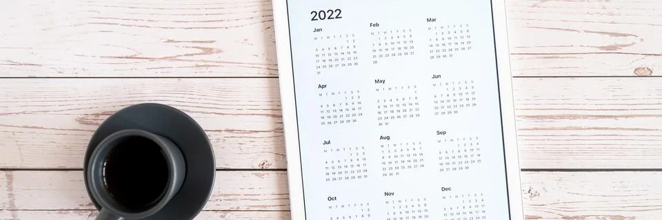 Tablet computer with an open app of calendar for 2022 year and cup of tea or  Stock Photos