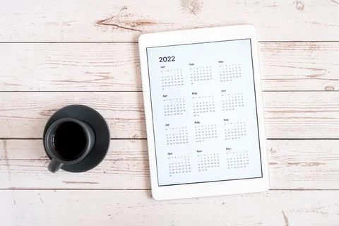 Tablet computer with an open app of calendar for 2022 year and cup of tea or  Stock Photos