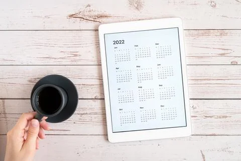Tablet computer with an open app of calendar for 2022 year and cup of tea or  Stock Photos
