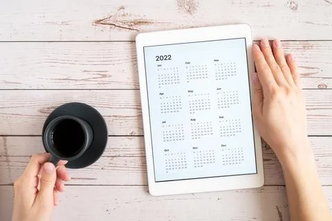 Tablet computer with an open app of calendar for 2022 year and cup of tea or  Stock Photos