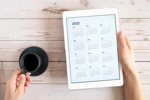 Tablet computer with an open app of calendar for 2022 year and cup of tea or  Stock Photos